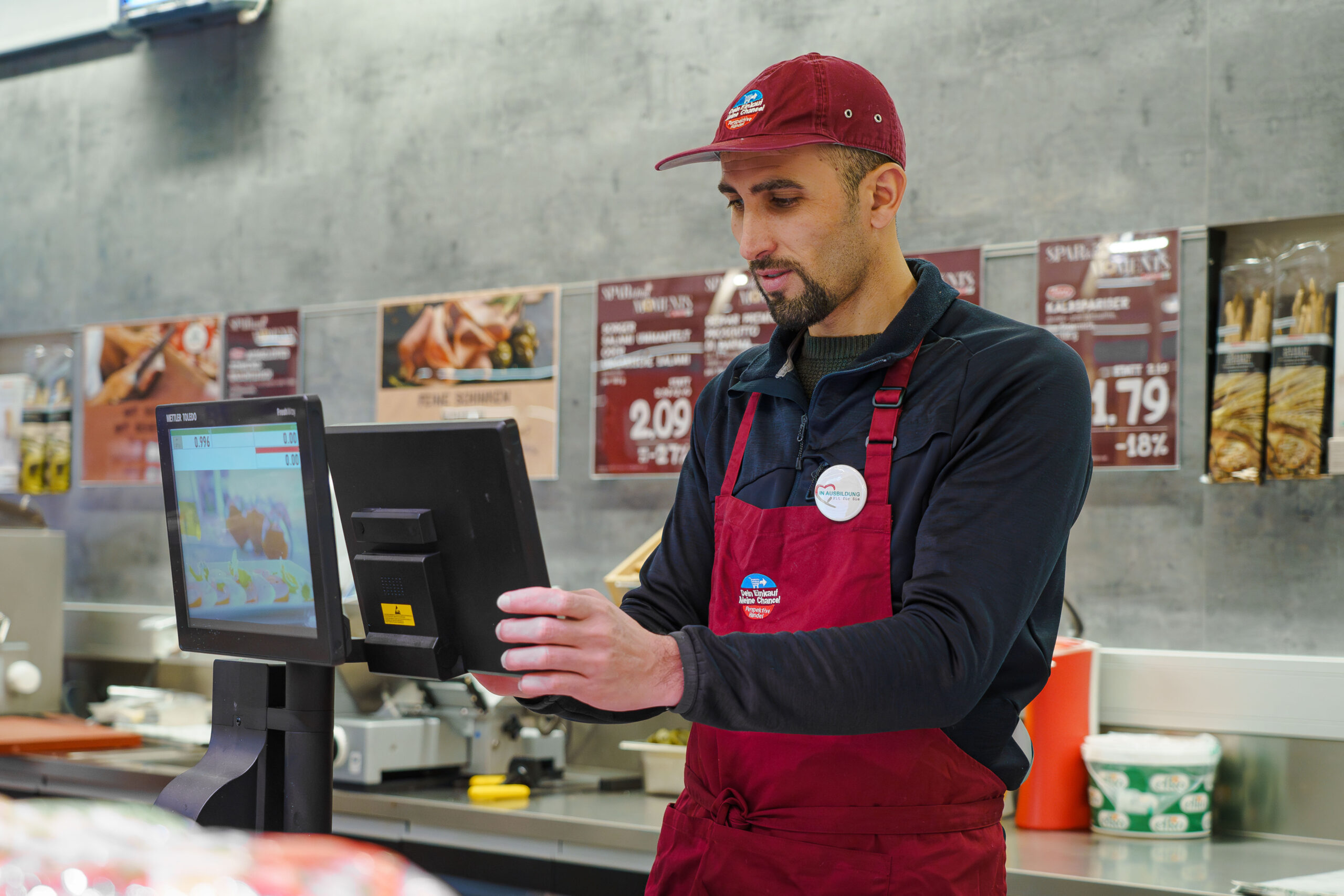 Ein Spar-Verkäufer wiegt Wurst ab