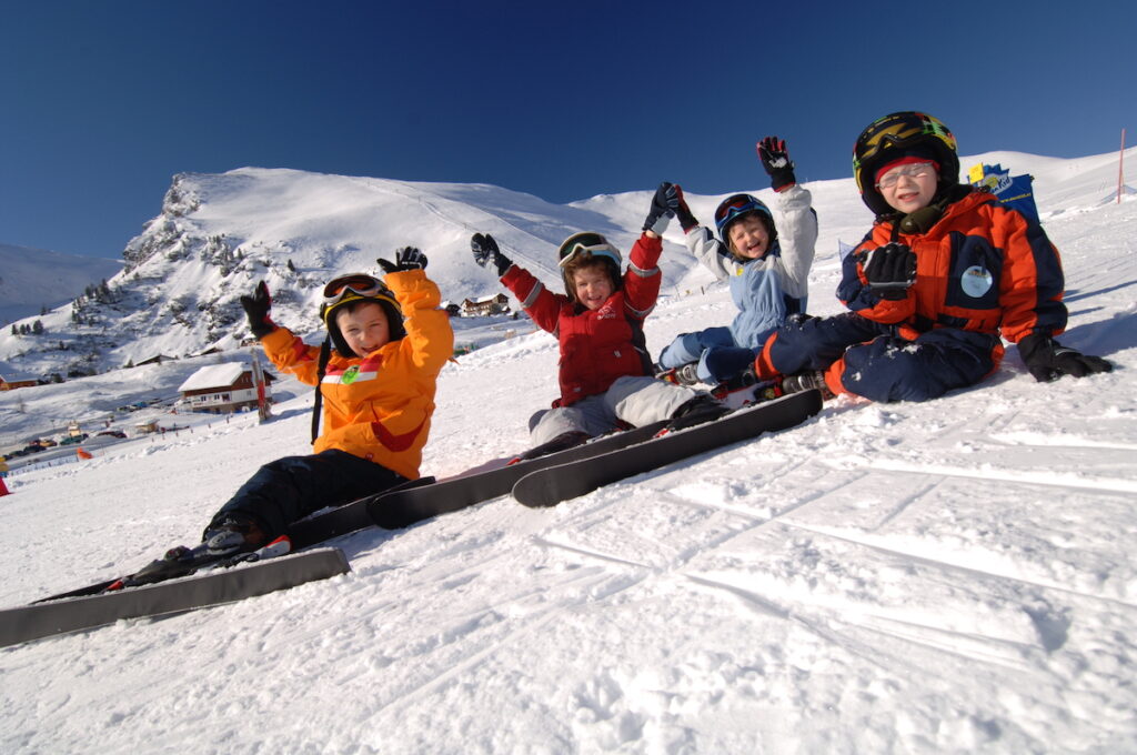 Vier Kinder setzten mit Ski im Schnee und haben Spaß