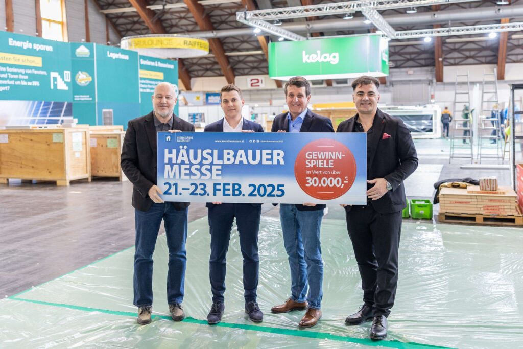 Vier Herren mit einem Schild auf dem steht "Häuslbauermesse"