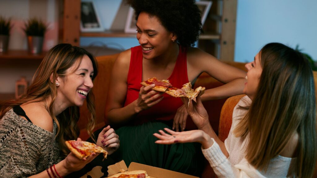 Galentinesday: Fröhliche Freundinnen, die zu Hause feiern und Pizza essen.