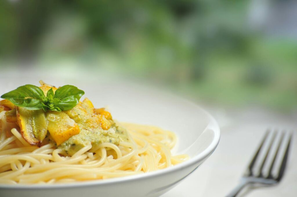 Frühlingsrezepte: Teller mit Pasta mit Gemüse und Basiliumblatt