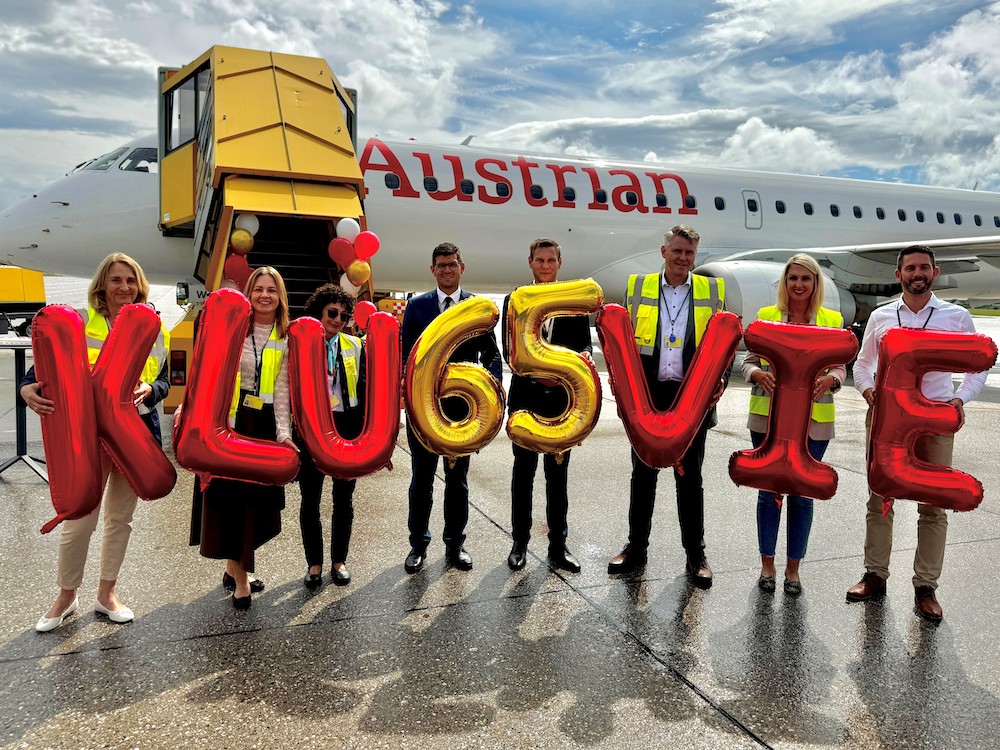 Menschen mit Luftballonen die die Zahl 65 anzeigen vor einem Flugzeug