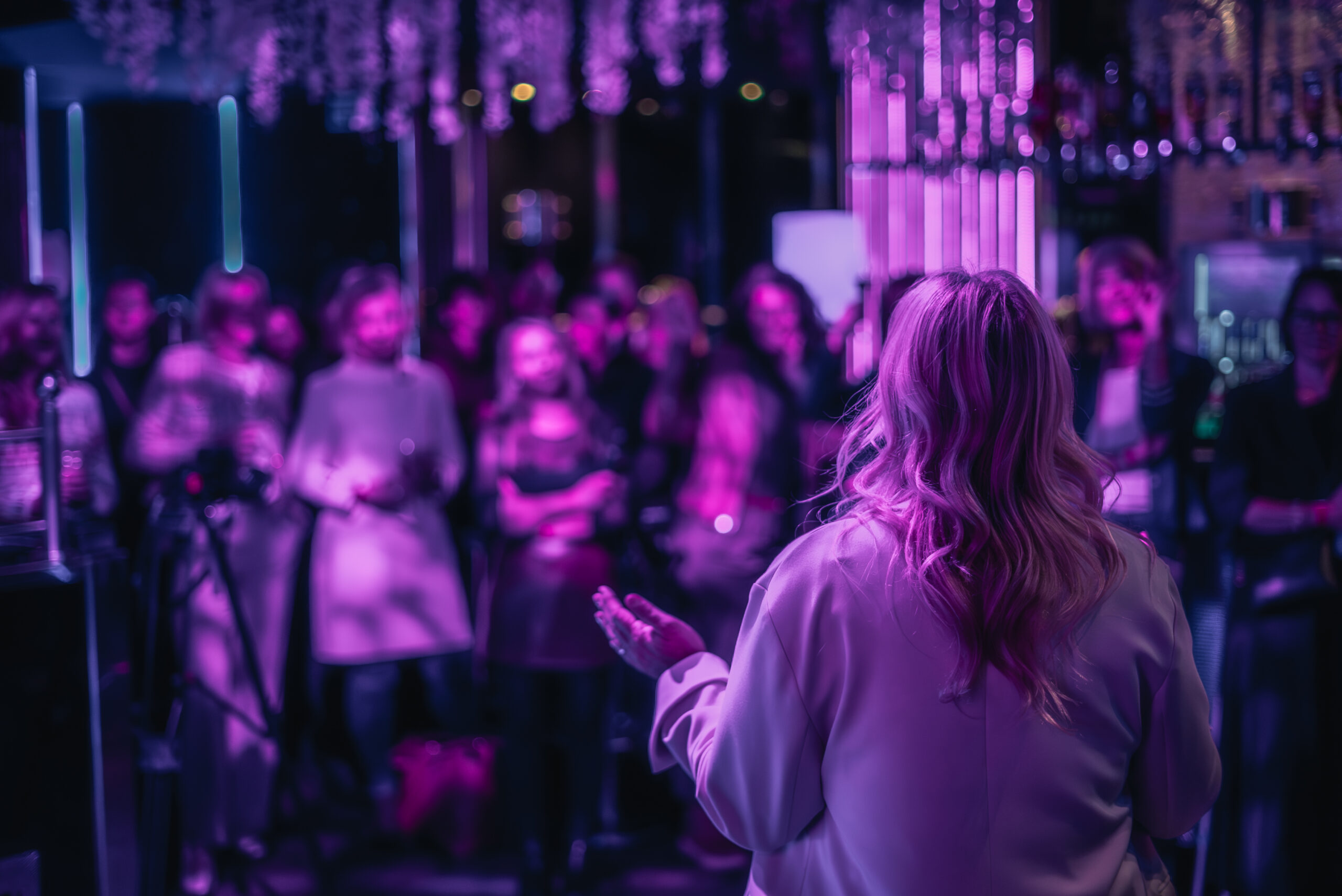 Im Bild zu sehen ist eine Menschengruppe in einer Disko und eine Vortragende