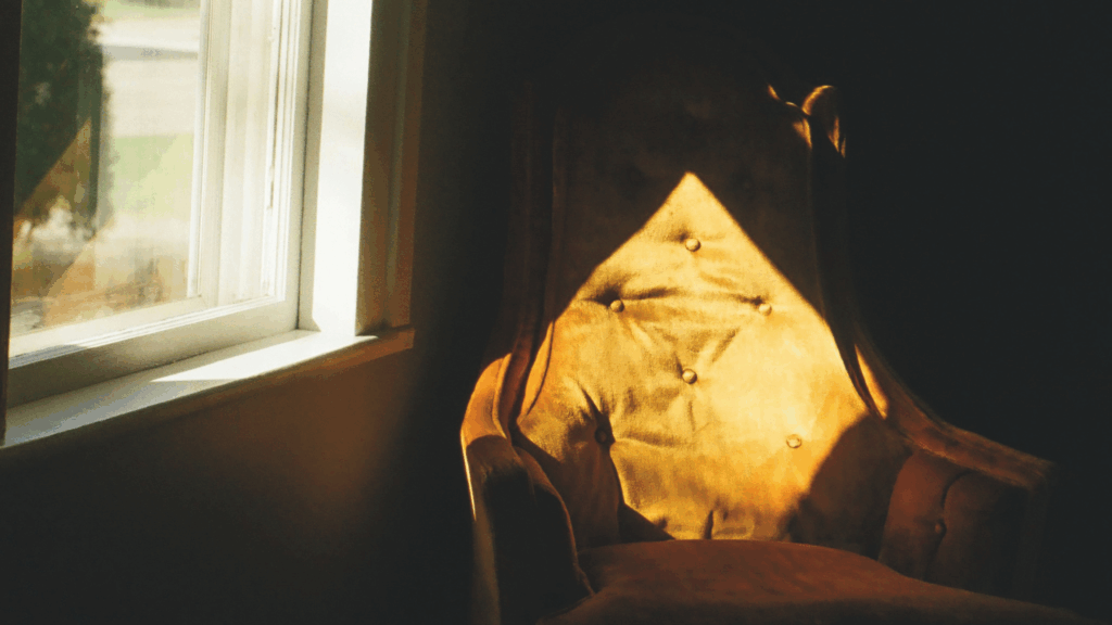 Sonne scheint durch ein Fenster auf einen Stuhl rechts daneben