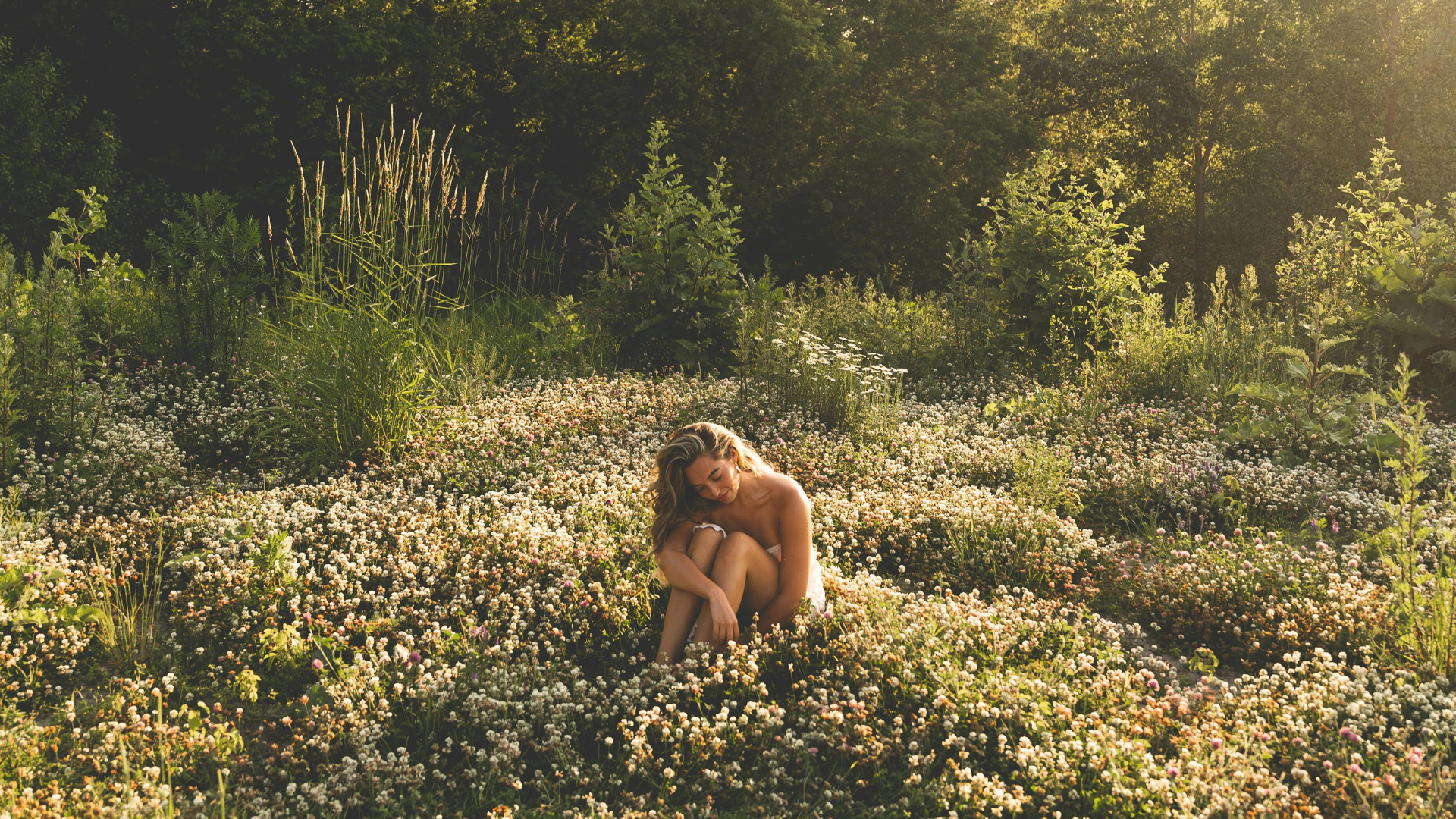 Eine Frau sitzt in einer Blumenwiese