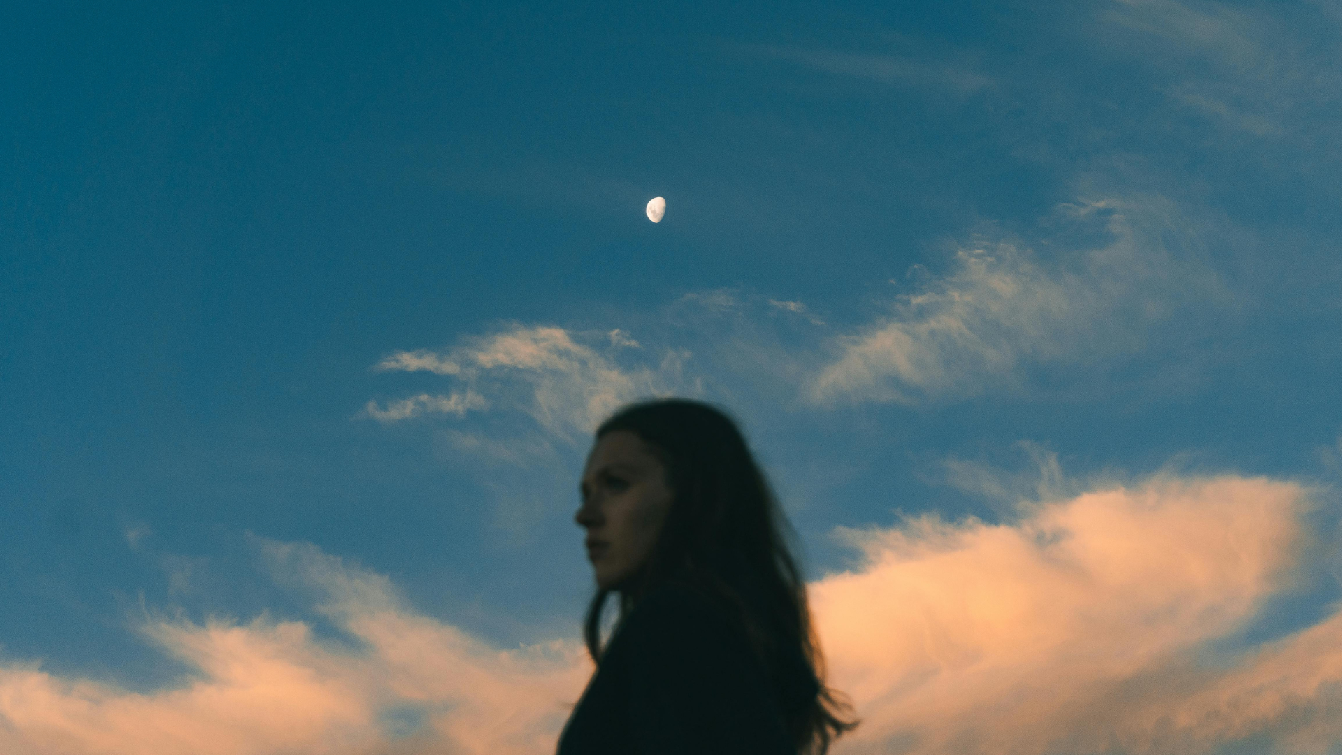 Frau vor einem Abend-Himmel mit Wolken und dem Mond